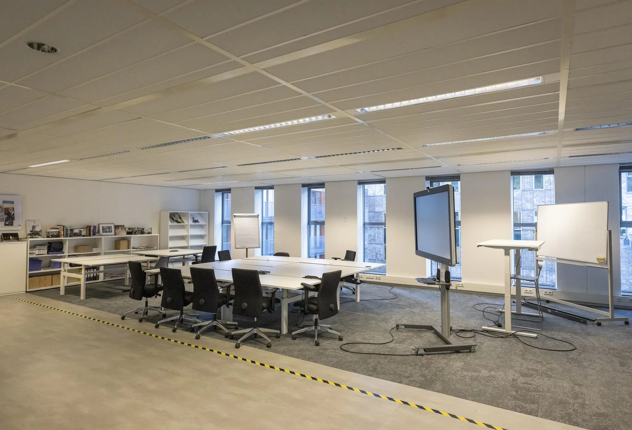 Moderne vergaderruimte aan de Prinses Beatrixlaan met tafels, stoelen, een digitaal scherm en whiteboards.